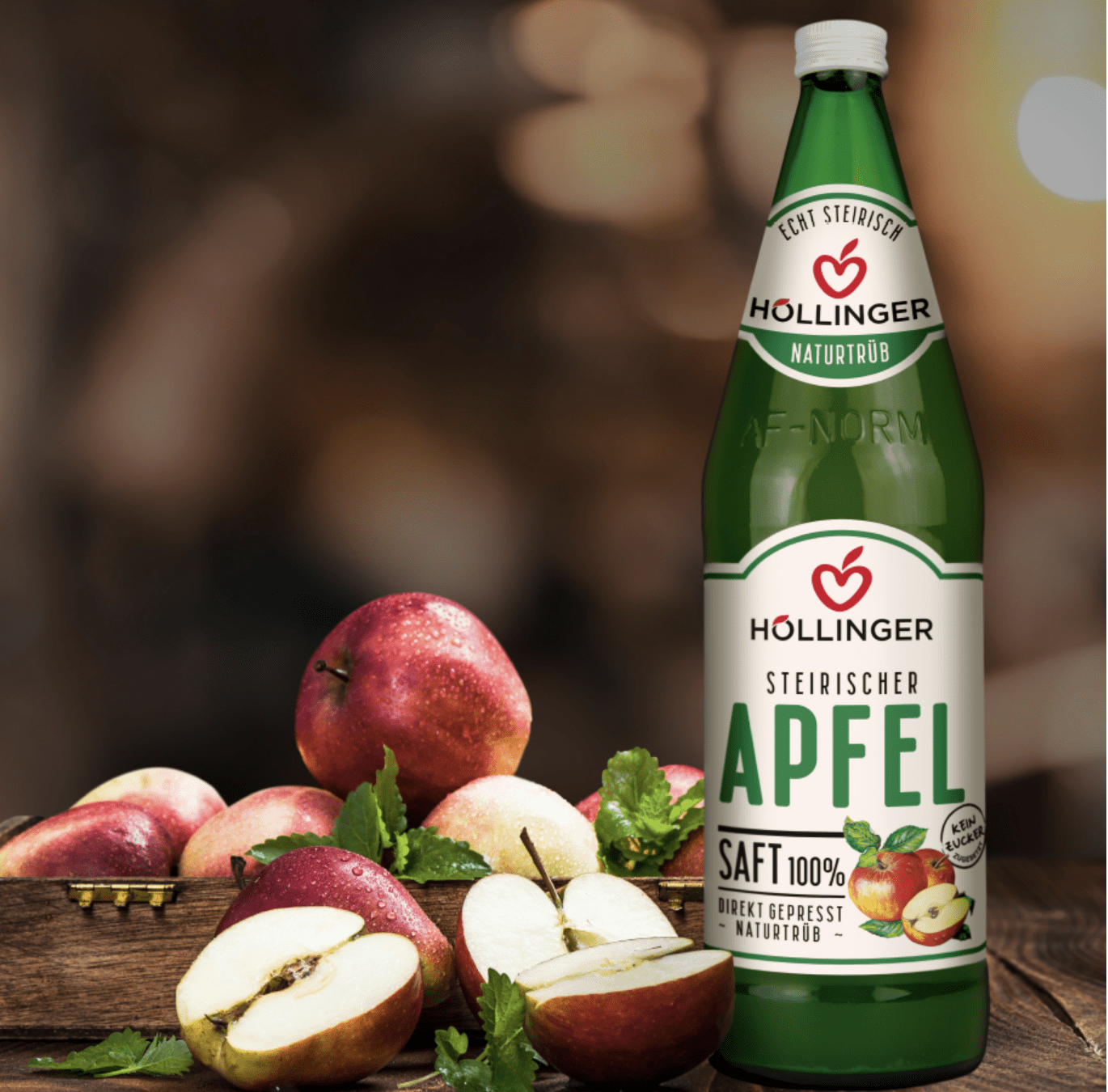 Höllinger steirischer Apfelsaft in der Mehrweg-Flasche auf einem Holz Tisch mit Äpfeln.