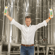 Gerhard Höllinger vor den Tanklager mit zwei Apfelsaft Packungen in den Händen