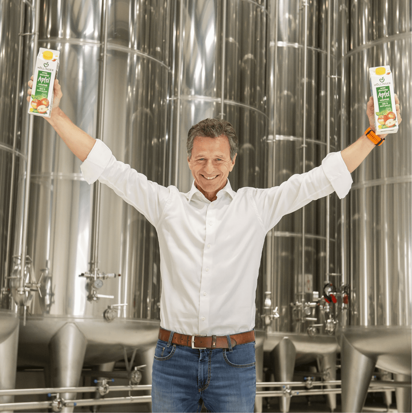 Höllinger Tanklager - Jetzt online bei Höllinger bestellen! Gerhard Höllinger vor den Tanklager mit zwei Apfelsaft Packungen in den Händen
