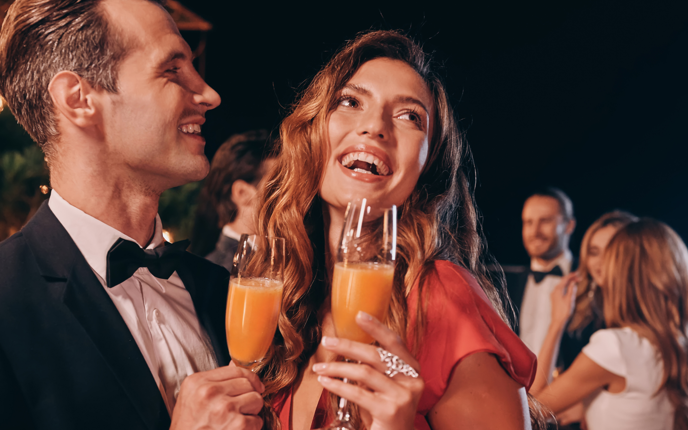 Paar in Abendgarderobe mit Bellini Secco auf einem Fest